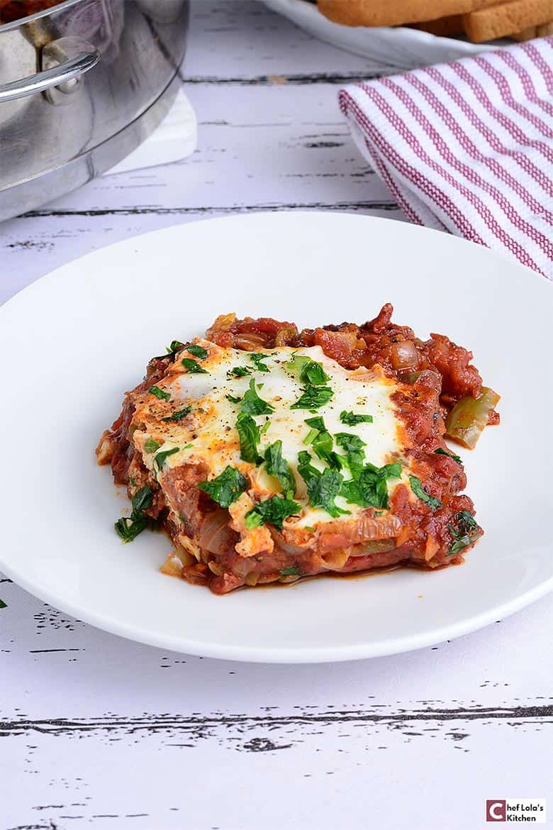 Shakshuka servida en un plato y adornada con perejil.