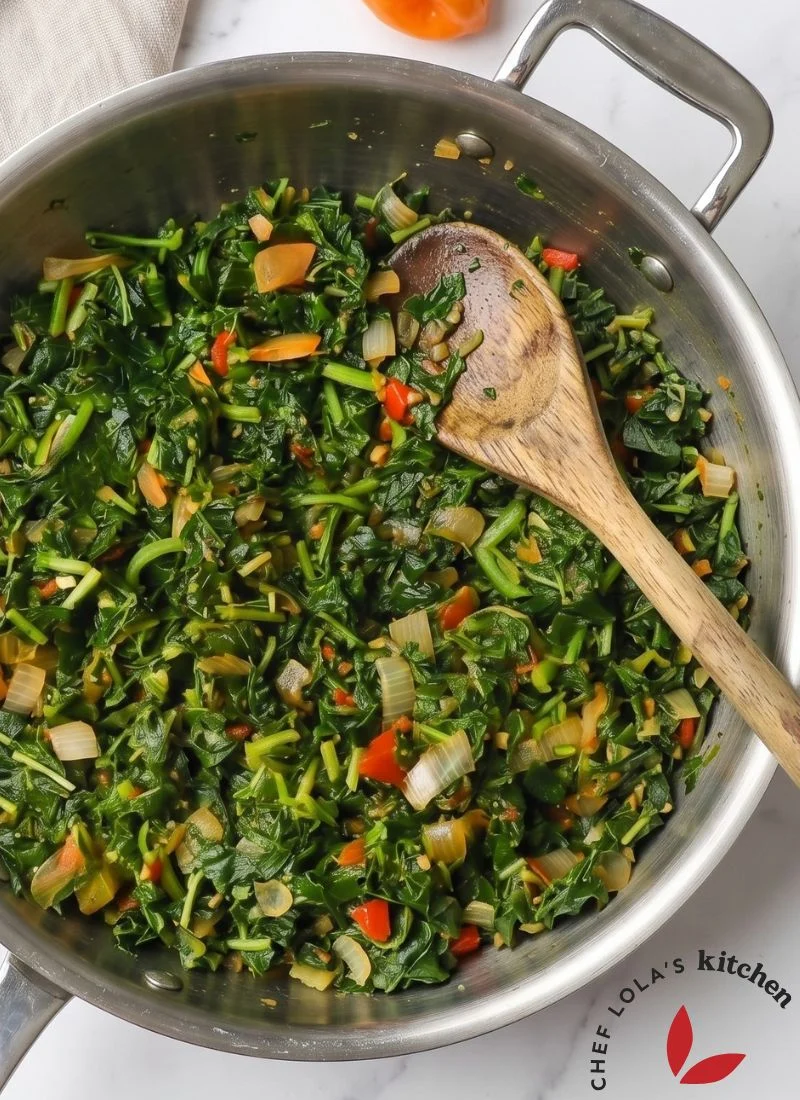 Una olla de callaloo jamaicano cocinado con cebollas, tomates, pimientos y condimentos aromáticos.
