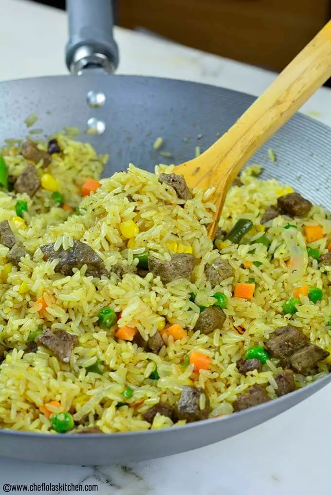 Foto de cerca de un delicioso arroz frito nigeriano cargado con verduras mixtas e hígado de res