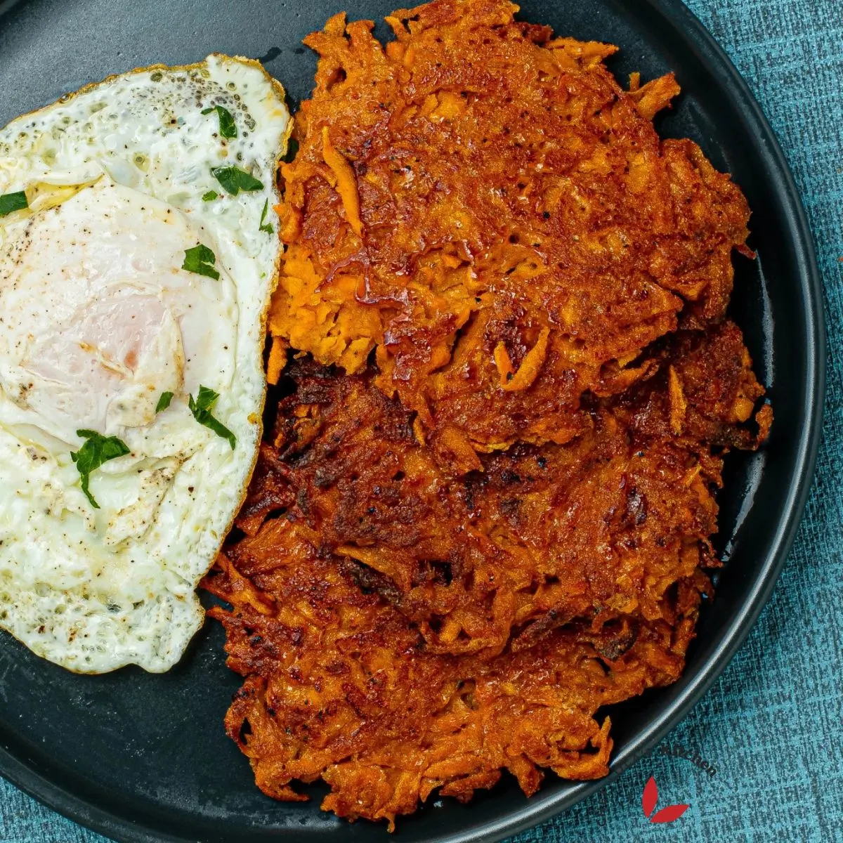 Croquetas de patata dulce servidas con huevos fritos y adornadas con perejil.